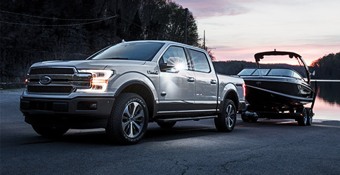 White F-150 towing boat out of the water