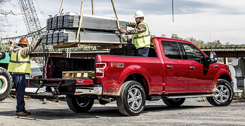 Workers loading heavy cargo into bed of 2020 Ford F-150