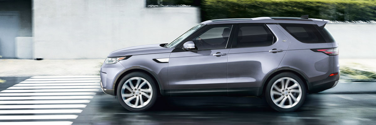 Land Rover Discover driving on city road, side view.