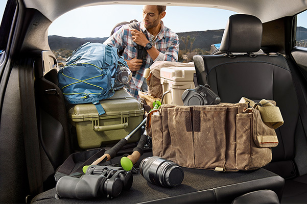 person unloading camping gear in the trunk of a toyota prius