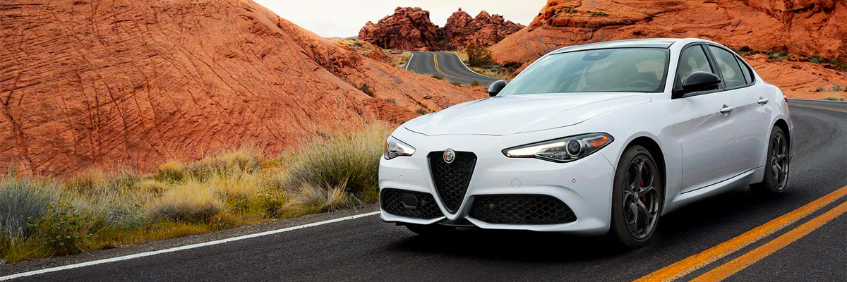 A 2021 Alfa Romeo Giulia Ti Sport Carbon in white, being driven through a winding mountain road.