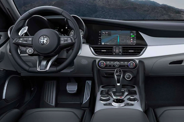 Display The interior of the 2021 Alfa Romeo Giulia Ti with Lusso Package focusing on the steering wheel, dashboard, touchscreen and center stack controls.