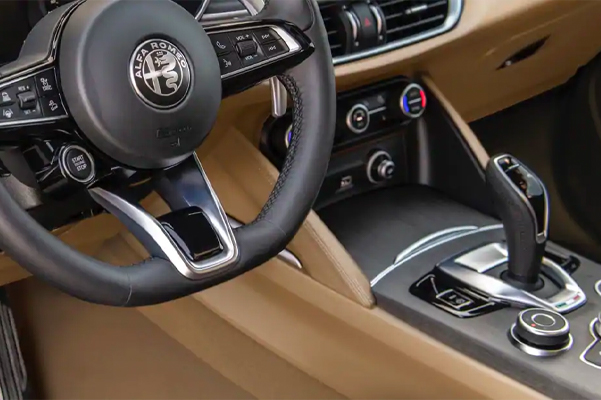 The interior of the 2021 Alfa Romeo Stelvio TI Lusso focusing on the steering wheel, dash and center console.
