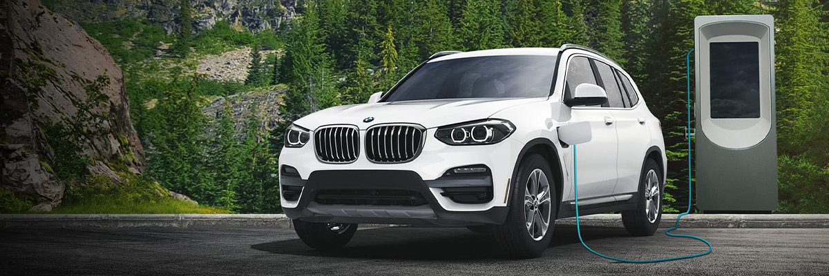2021 BMW X3 xDrive30e at a charging station with trees in the background