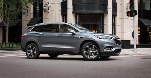 Side profile of a 2021 Buick Enclave taking a corner in the middle of the city