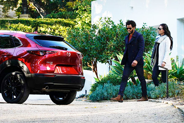 Young couple walkin up to their new red Mazda CX-30