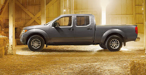 Side profile of a 2021 Nissan Frontier parked in a barn
