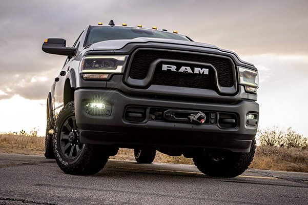 Display A low-angle view of a 2021 Ram 2500 being driven on a road with a menacing sky overhead.