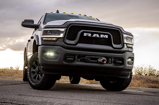 Display A low-angle view of a 2021 Ram 2500 being driven on a road with a menacing sky overhead.
