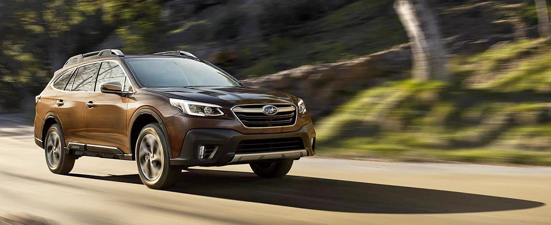2021 Subaru Outback driving on a road with trees in the background