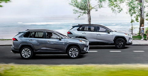 Side profile of two 2021 Toyota RAV4 vehicles driving along the water