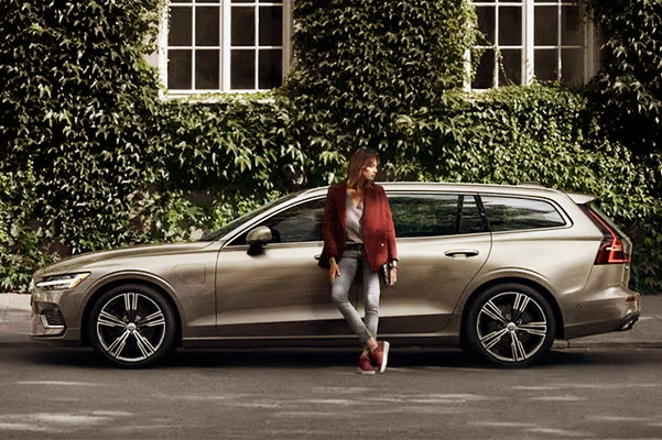 Young woman standing against her new Volvo parked on the street