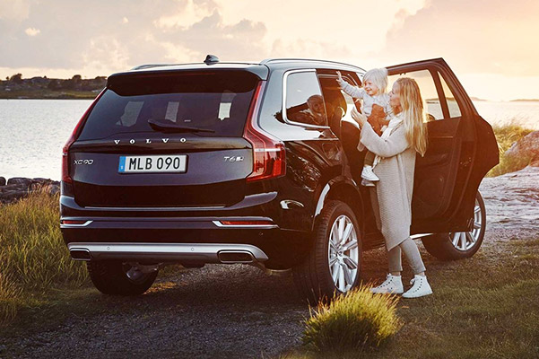 Woman and her baby enjoying a sunset by lake side with their new Volvo