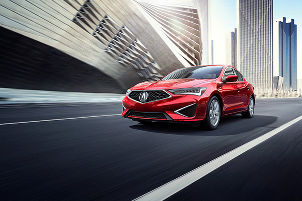 A red 2022 Acura ILX driving down a city street
