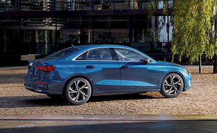 rear 3/4 angle of a blue metallic 2022 A3 parked outside of a building