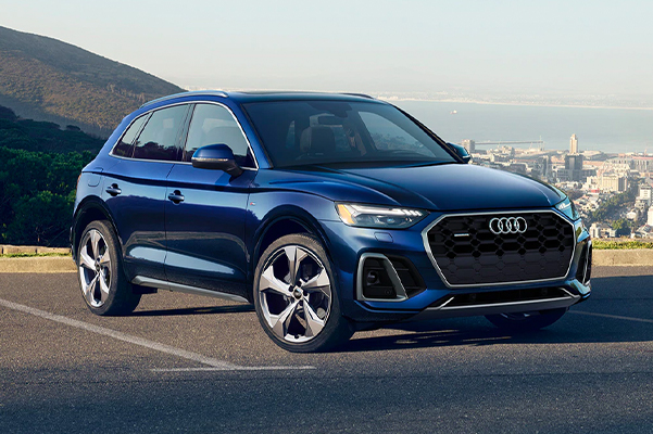 Exterior shot of a 2022 Audi Q5 parked in a parking lot with a city in the distant background.