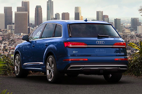 Exterior shot of a parked 2022 Audi Q7 with a city in the background.