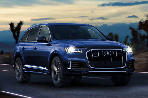 Exterior shot of a 2022 Audi Q7 driving down a road at sunset.