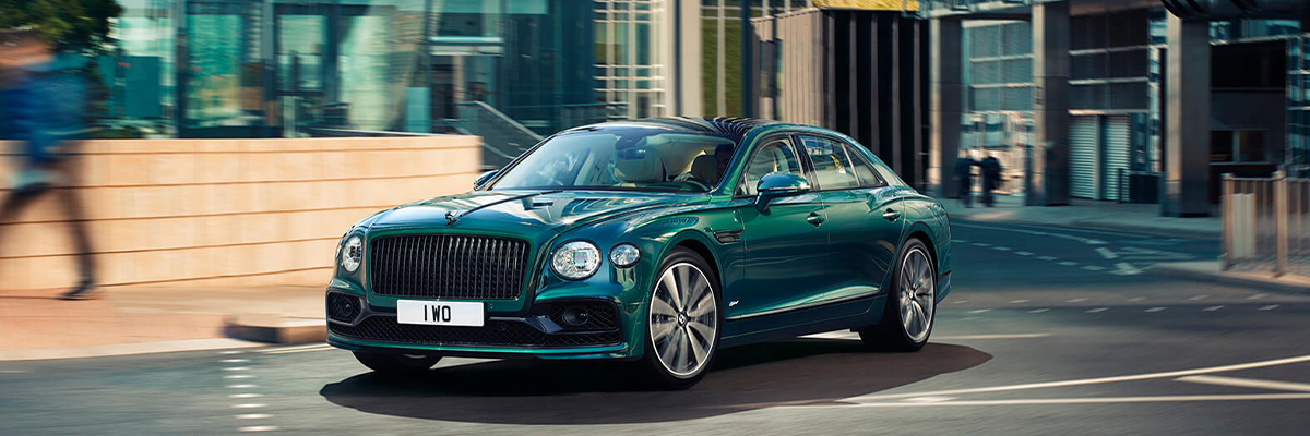 Exterior shot of a 2022 Bentley Flying Spur Hybrid taking a turn in a city.