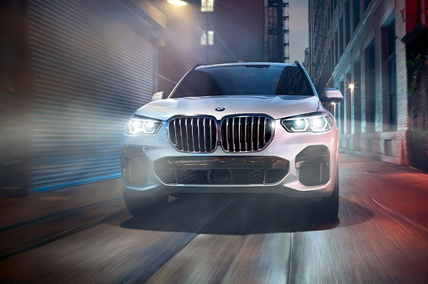 Front shot of 2022 BMW X5 driing down alleyway at night.