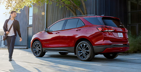 Man Walking by 2022 Chevy Equinox Small SUV in Red: Rear Three-Quarter View
