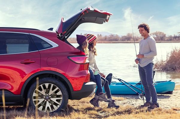 People standing outside a Ford SUV at a lake