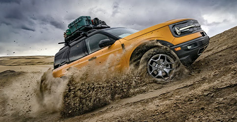 The 2022 Ford Broncoâ„¢ Sport shown driving up a dirt hill