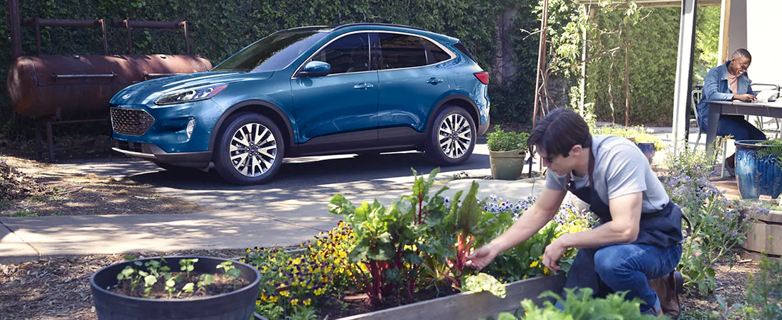 2022 Ford Escape Titanium in Atlas Blue Metallic parked in a backyard with people relaxing