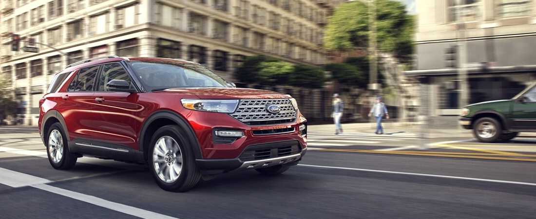 A 2022 Ford Explorer Limited in Rapid Red being driven down a city street