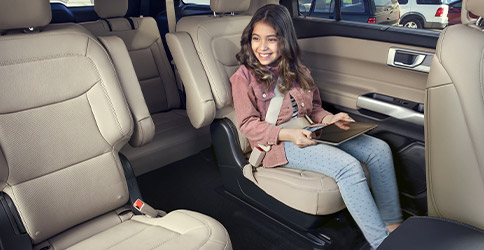 2022 Ford Explorer with a girl sitting in the second-row seat with a tablet in her lap