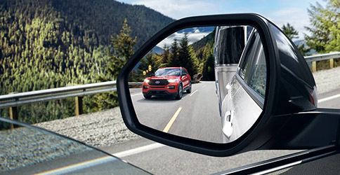 2022 Ford Explorer close up of an auto-dimming sideview mirror showing the reflection of a 2022 Ford Explorer in Lucid Red