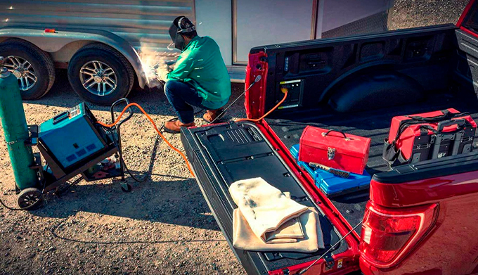a person welding a trailer near a 2022 Ford F-150