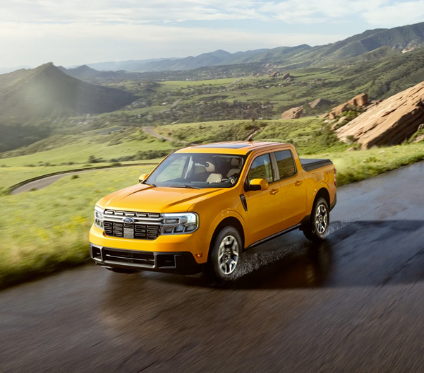 Cyber Orange 2022 Ford Maverick on a road winding through a hilly, scenic landscape