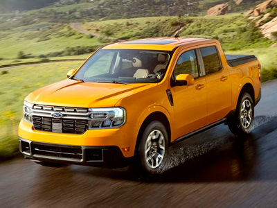 Cyber Orange 2022 Ford Maverick on a road winding through a hilly, scenic landscape