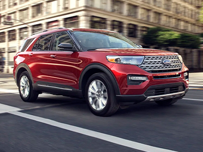 A 2022 Ford Explorer Limited in Rapid Red being driven down a city street