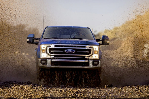 2022 Ford Super Duty® LARIAT Crew Cab with Tremor™ Off-Road Package in Atlas Blue being driven through dirt