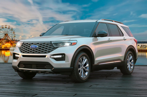 2022 Ford Explorer parked near a body of water with a ferris wheel in the background.
