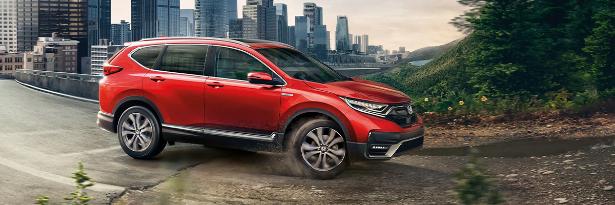 2022 Honda CR-V Hybrid driving down a road with a city background