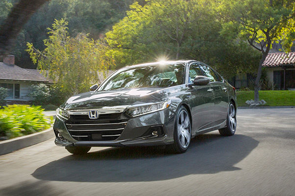 Front driver-side view of the 2022 Honda Accord Hybrid Touring in Modern Steel Metallic, driving through residential neighborhood.