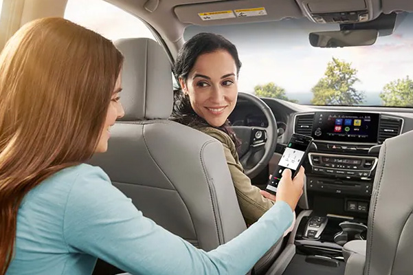 Daughter in back seat showing her mother how to use the CabinControl® smartphone app available in the 2022 Honda Pilot