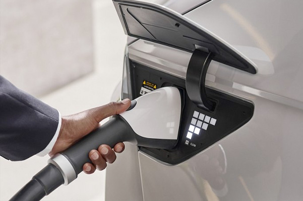 Electric car or ev is charging at station. Man use the white power cable and plug on nature background.