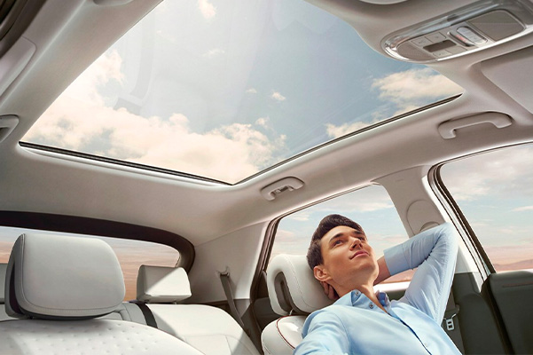 Person reclining in their driver's seat looking through their panoramic glass sunroof