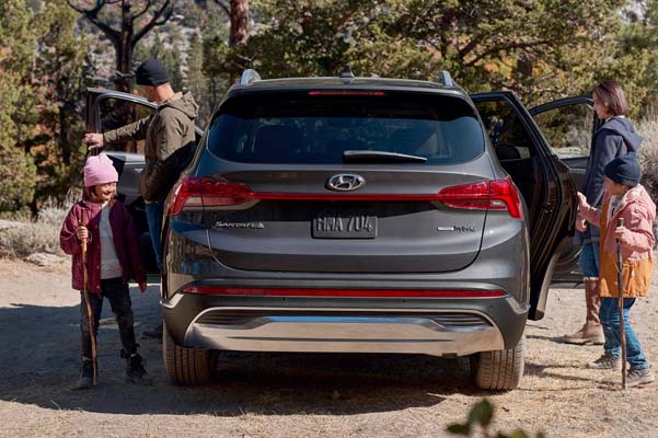 Rear view of the 2022 Santa Fe Hybrid as a family is getting out of the car