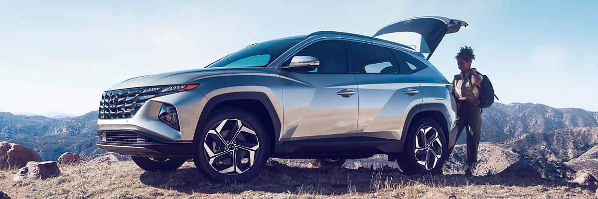 2022 Hyundai Tucson off-road on the mountainside with someone grabbing backpack from trunk