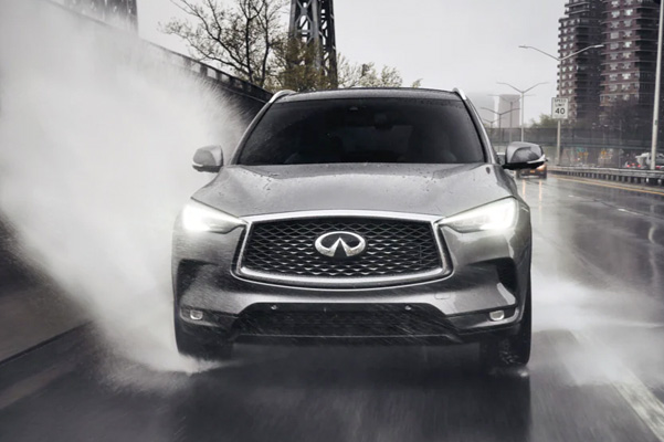 Front profile view of 2022 INFINITI QX50 driving through a puddle highlighting Intelligent AWD feature
