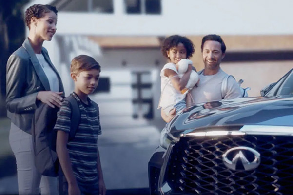 Family standing beside the 2022 INFINITI QX60 shown in blue color