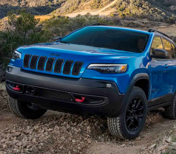 Display The 2022 Jeep Cherokee Trailhawk being driven off-road on a dirt trail.
