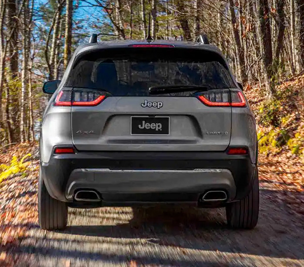 Display The 2022 Jeep Cherokee Limited being driven off-road through the woods on a clear autumn day.
