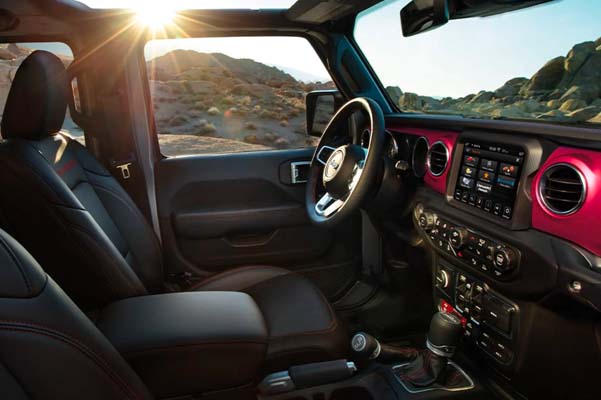 The interior of the 2022 Jeep Gladiator Rubicon with its top off and magenta accents around the vents. 