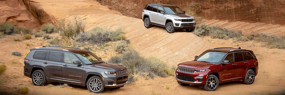 A 2022 Jeep Grand Cherokee Summit Reserve, a 2022 Jeep Grand Cherokee L Summit Reserve and a 2022 Jeep Grand Cherokee Trailhawk 4xe parked off-road on a rocky slope.